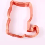 Ein rosegoldener Ausstecher in Form einer Katze auf weißem Hintergrund.