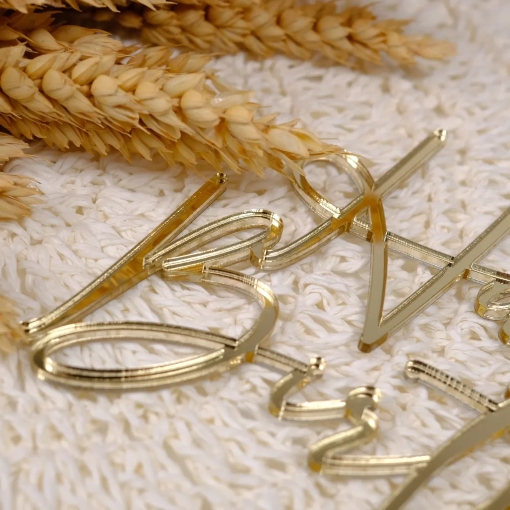 Nahaufnahme eines Cake Toppers aus goldenem Acryl mit einem Schriftzug.