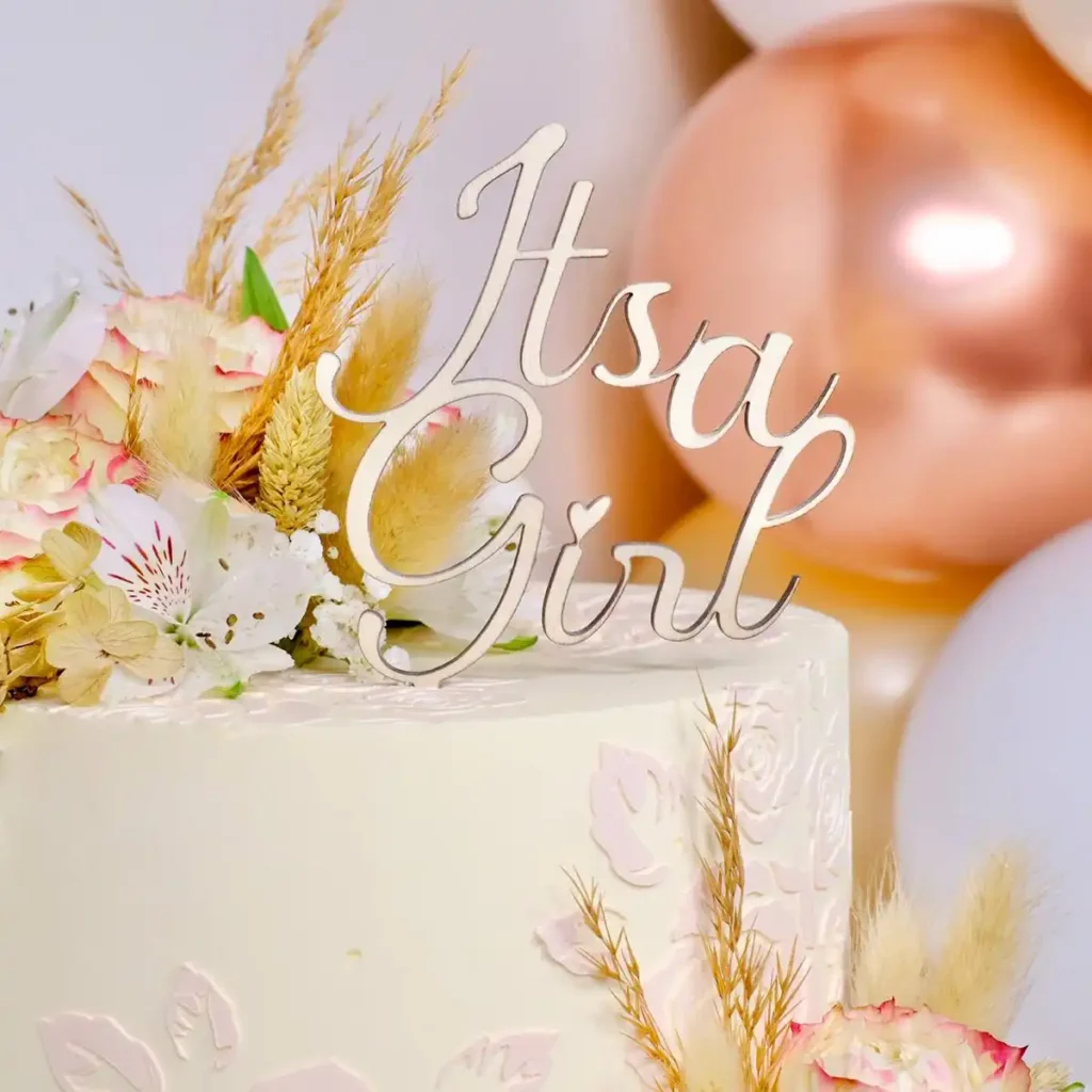 Ein Cake Topper aus Holz mit der Aufschrift "It's a Girl" auf einer Torte.