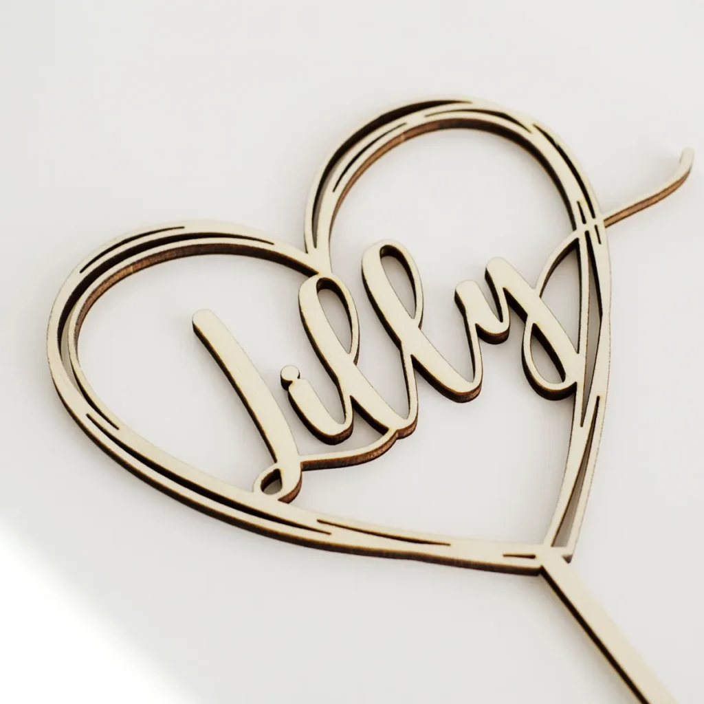 Ein Cake Topper aus Holz in Form eines Herzens mit Schriftzug "Lilly".