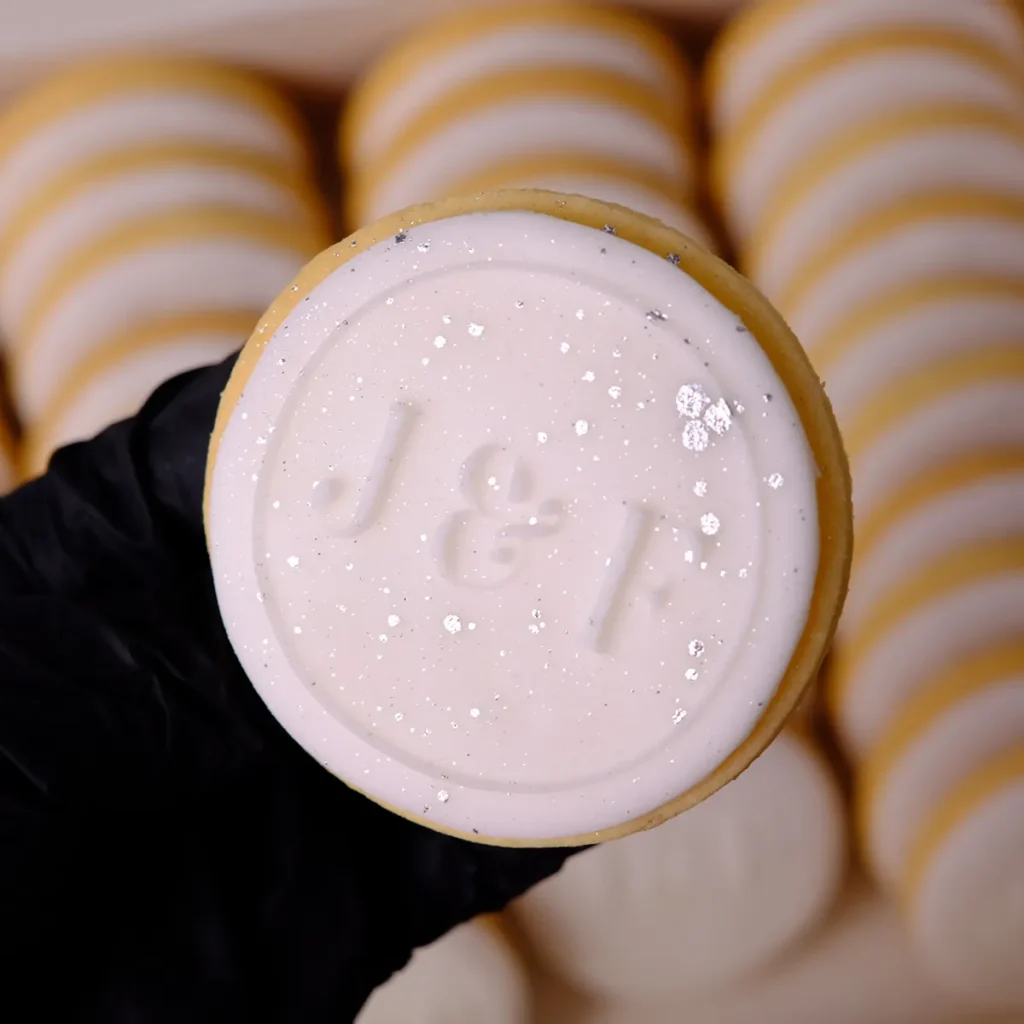 Ein runder, rosaner Keks mit geprägtem "J & F".